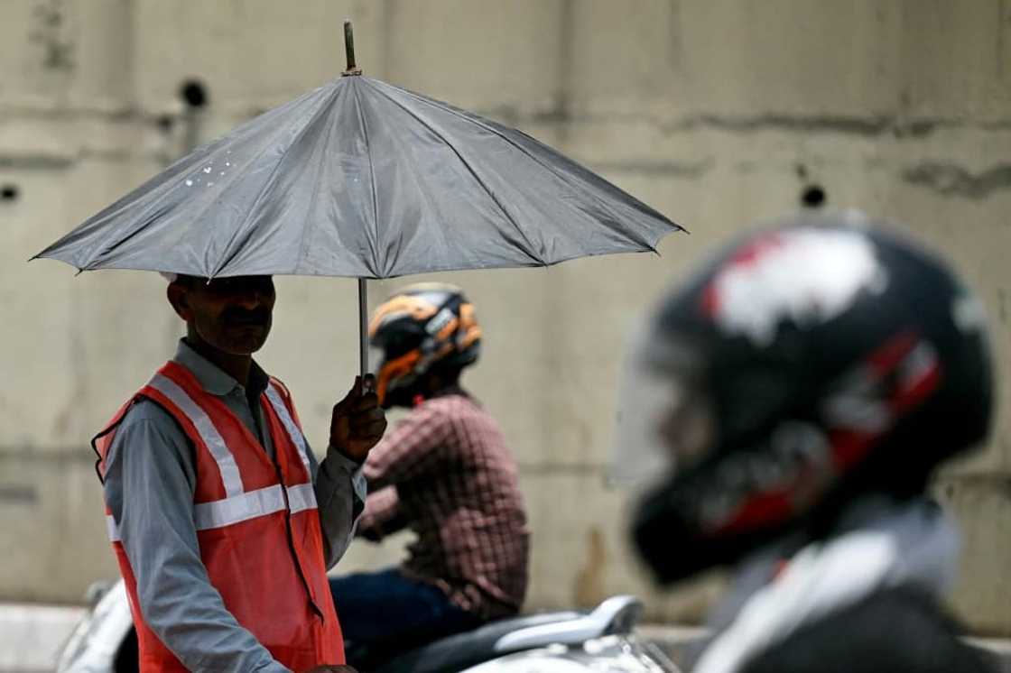 As developing countries urge increases in climate aid, a toll booth worker takes shade under an umbrella during a record heatwave in Delhi