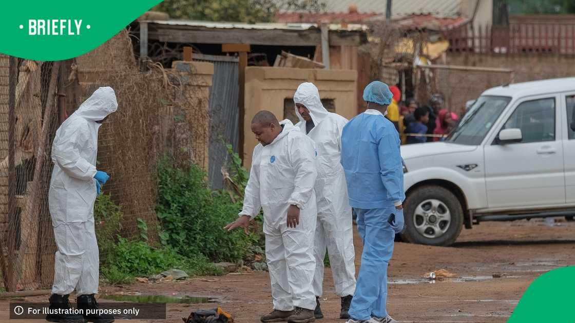 South African Police Service (SAPS) Forensic Pathology Services members gesture at the scene of an attack at a tavern in Bekkersdal on December 21, 2025