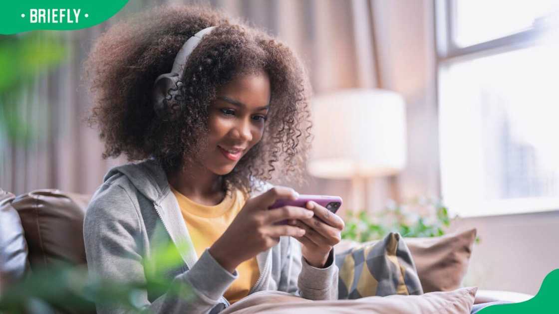 A cheerful young adult playing with her phone