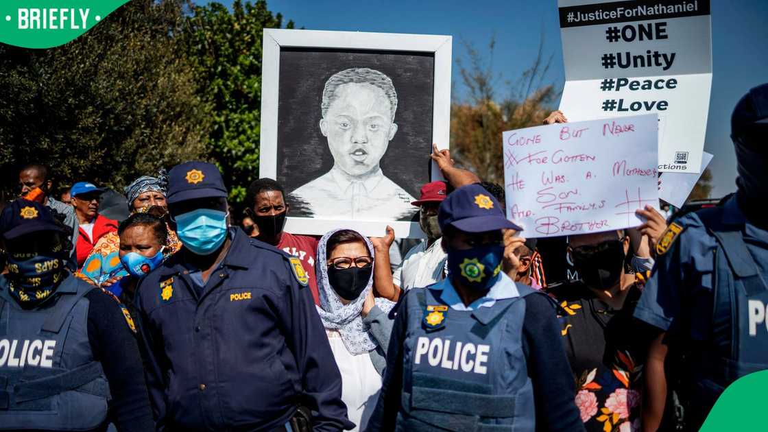 Community members hold a placard with an image of Nathaniel Julies during his funeral service in Eldorado Park
