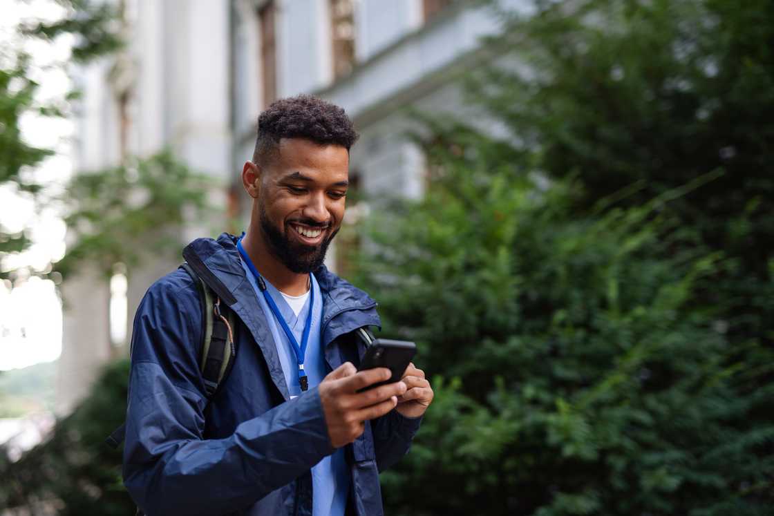 A man smiling at his phone. A man smiling at his phone.