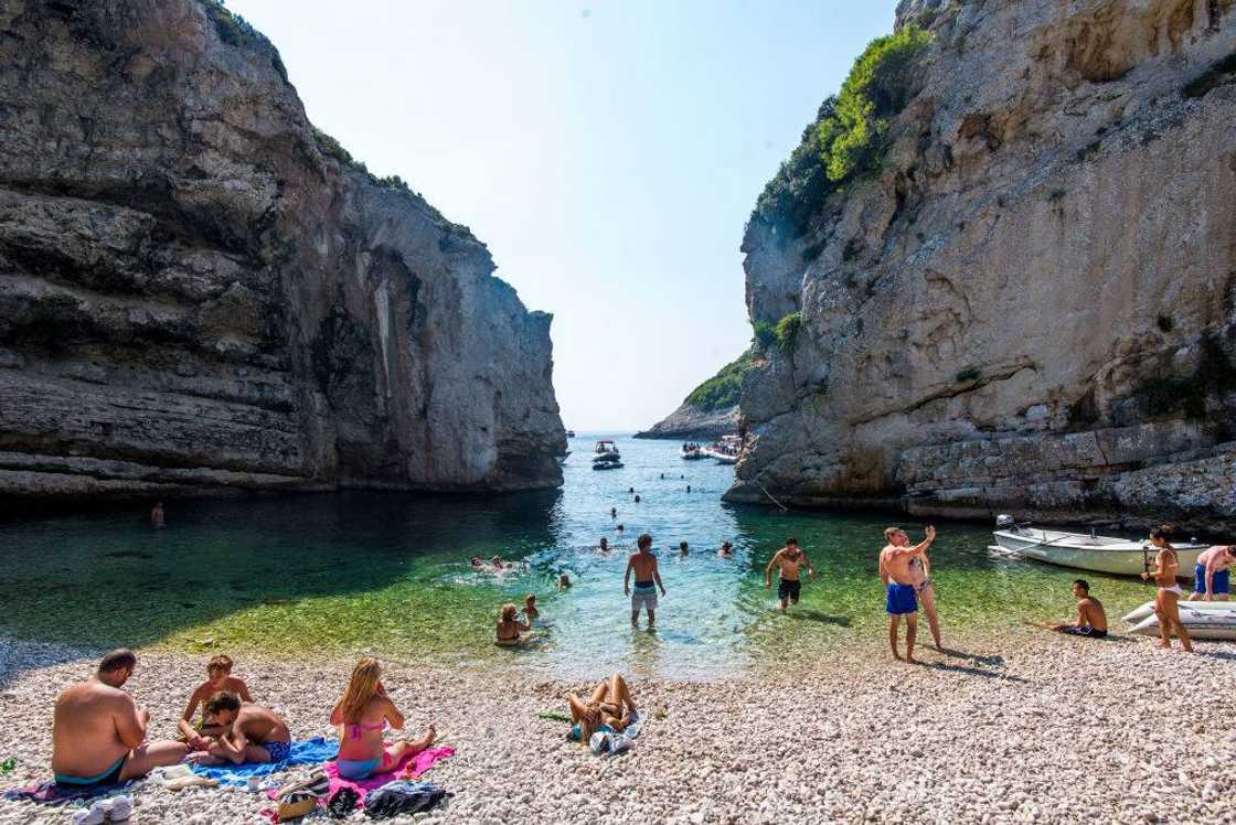 Tourists swimming and sunbathing on Stiniva beach in Vis, Croatia