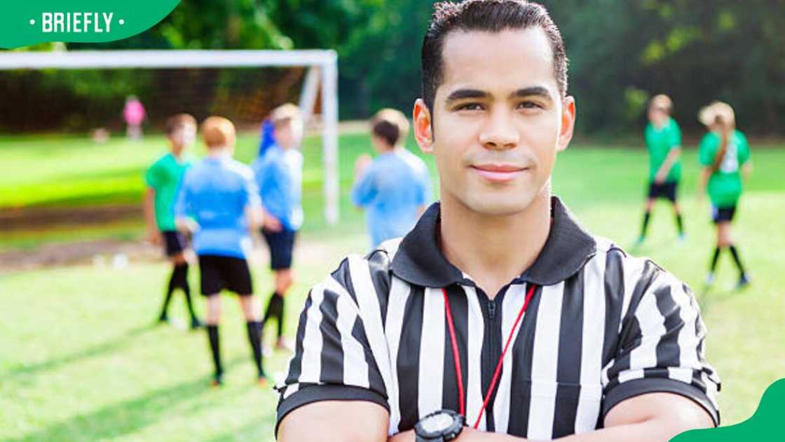 Referee stands on the field during soccer game.