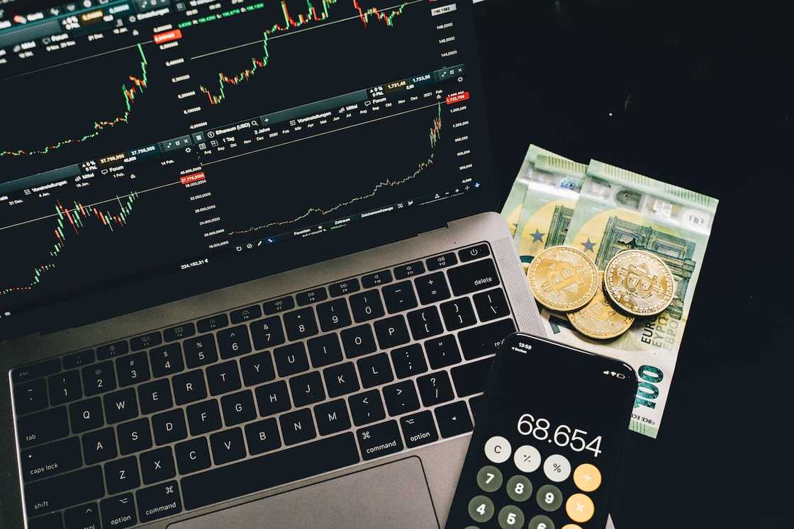 Bitcoins and paper money beside a cellphone and laptop
