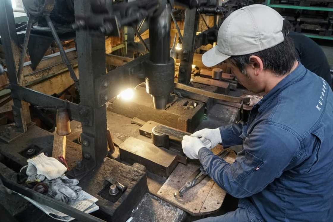 Yoshihiro Yauji places a 'santoku', a multipurpose knife, under a spring hammer, continuing a tradition dating back centuries