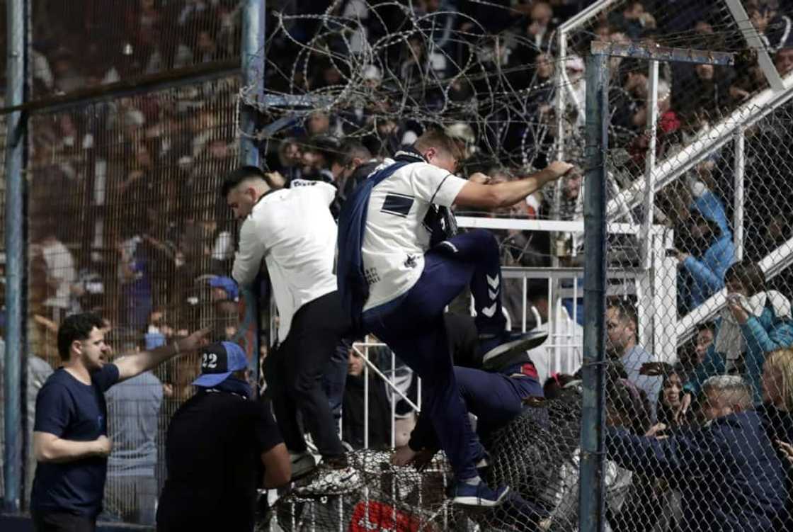 Spectators of a Boca Juniors soccer match against Gimnasia y Esgrima react after Argentina police used tear gas to break up violent clashes that began outside the stadium in La Plata but then entered the venue, leaving one person dead