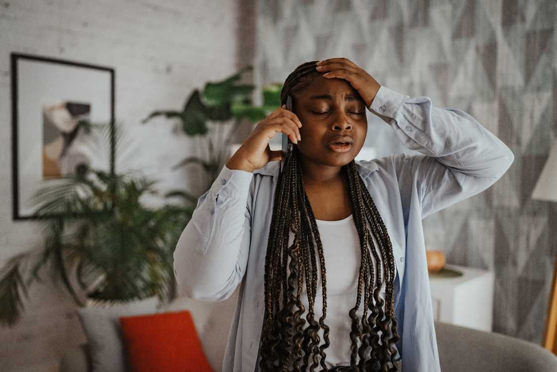 A worried woman holding her forehead while talking on the phone