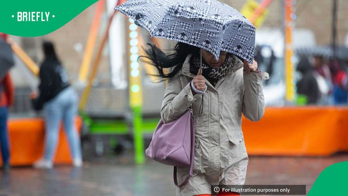 A woman holds an umbrella and struggles to walk against the wind in Bonn, Germany, on October 25, 2025