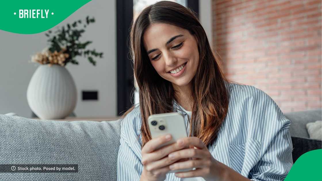 A woman smiling at her phone.