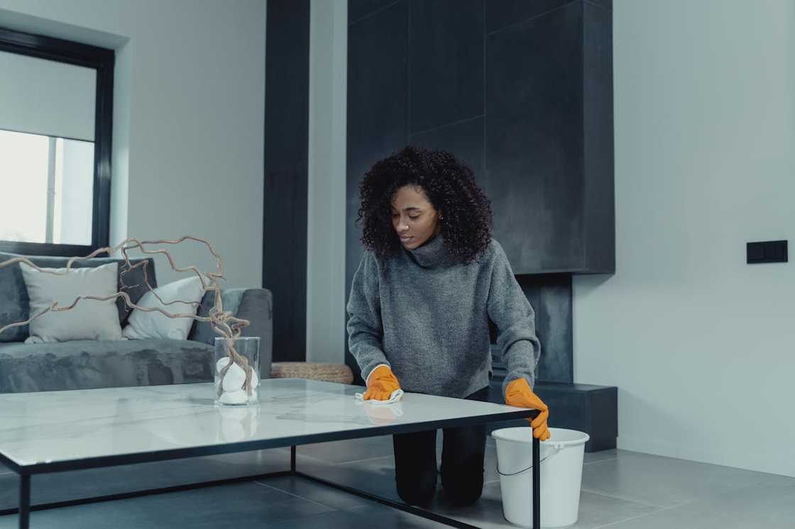 A woman in grey sweater cleans and arranges the living room. A woman in grey sweater cleans and arranges the living room.