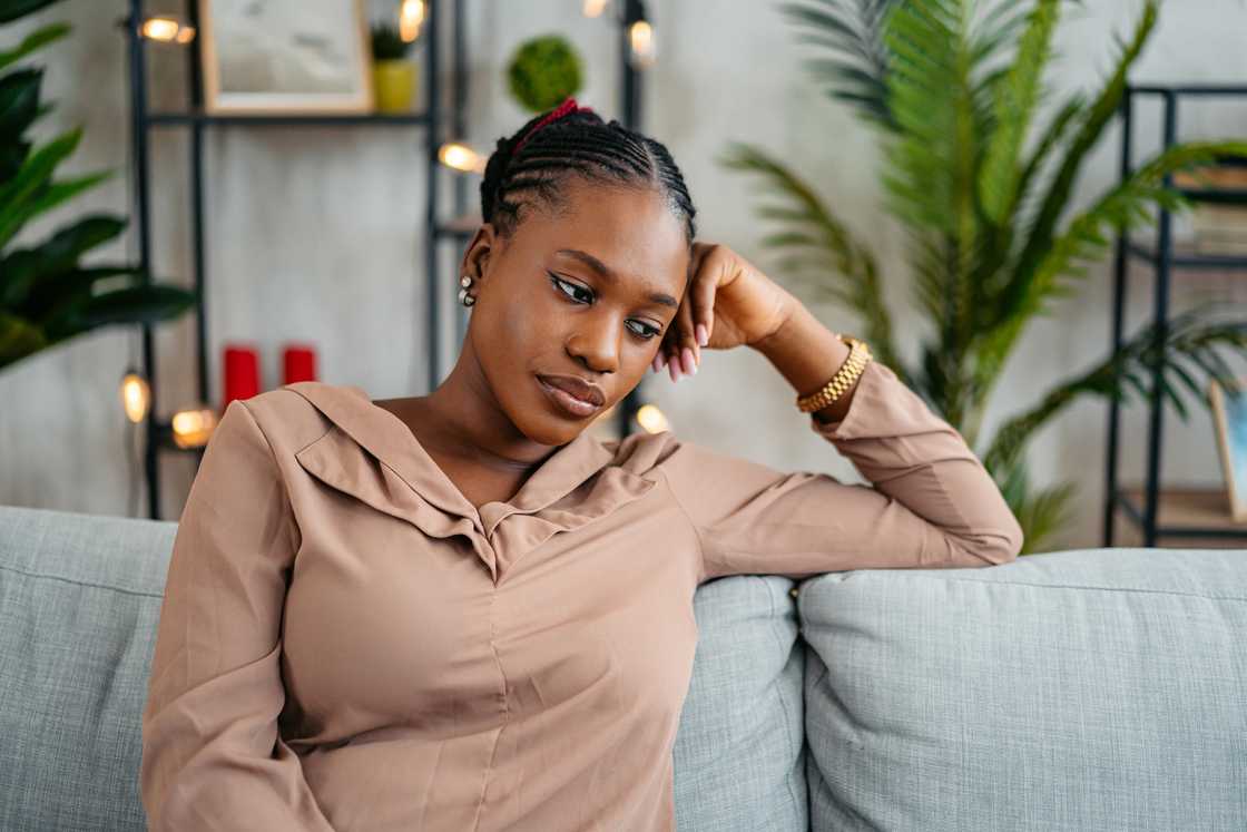 A woman sitting on the sofa at home and sulking. A woman sitting on the sofa at home and sulking.