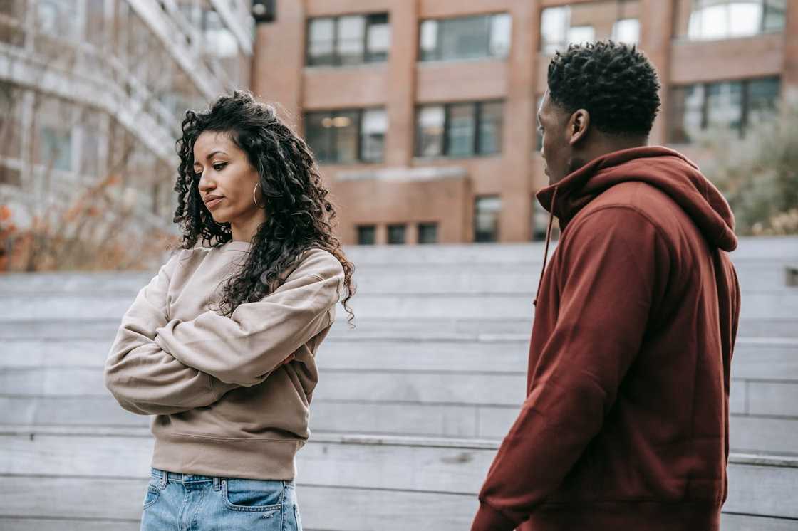 A woman folds her arms while facing a man during a tense conversation. A woman folds her arms while facing a man during a tense conversation.