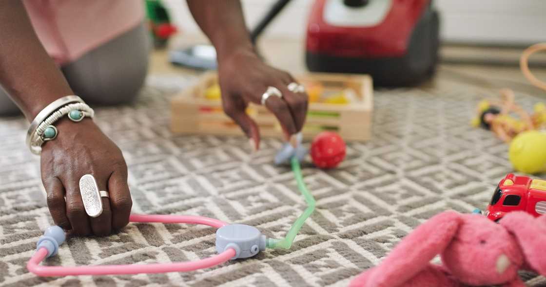 A black woman is cleaingn the playroom