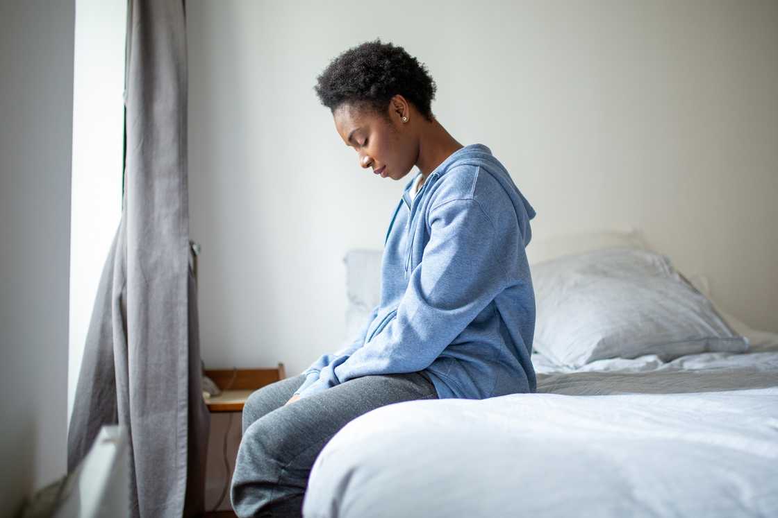 A distressed woman sitting on the edge of the bed A distressed woman sitting on the edge of the bed