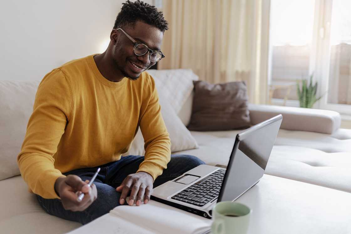 A young businessman working on a laptop computer at home.