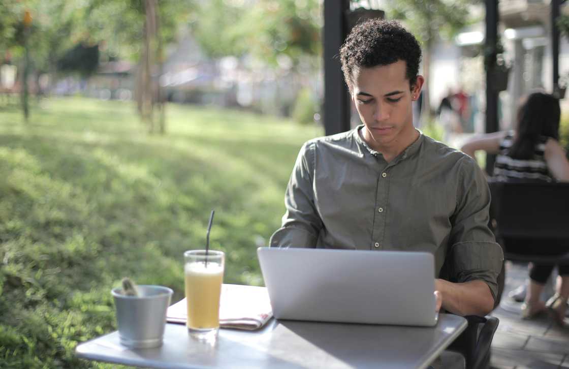 A male freelancer using a laptop in the street cafe.