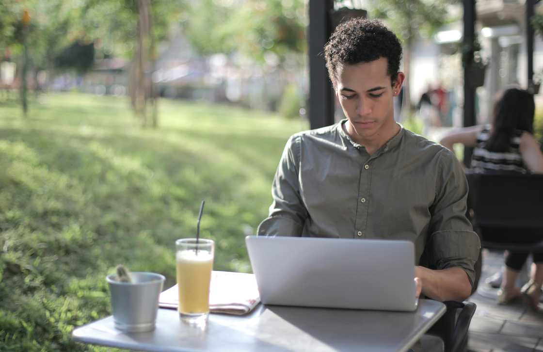 A male freelancer using a laptop in the street cafe. A male freelancer using a laptop in the street cafe.