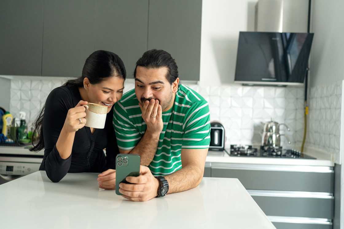 Couple smiling at a phone. Couple smiling at a phone.