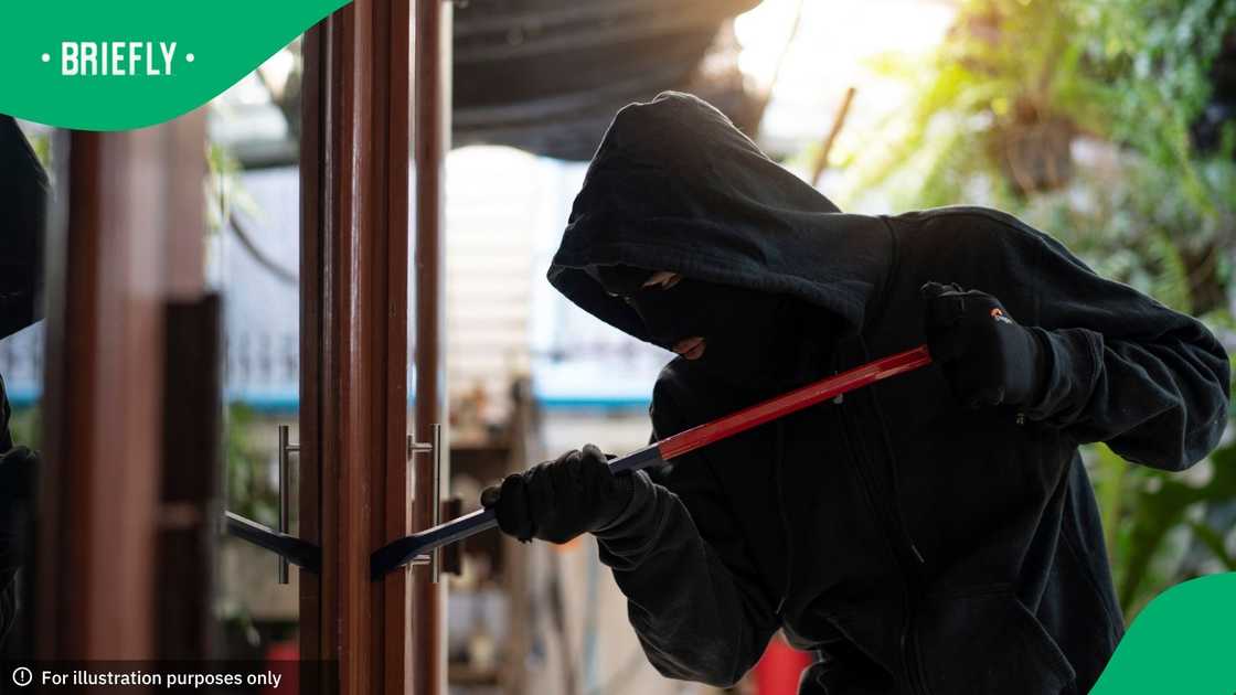 Burglar wearing black clothes and leather coat breaking in a house Burglar wearing black clothes and leather coat breaking in a house