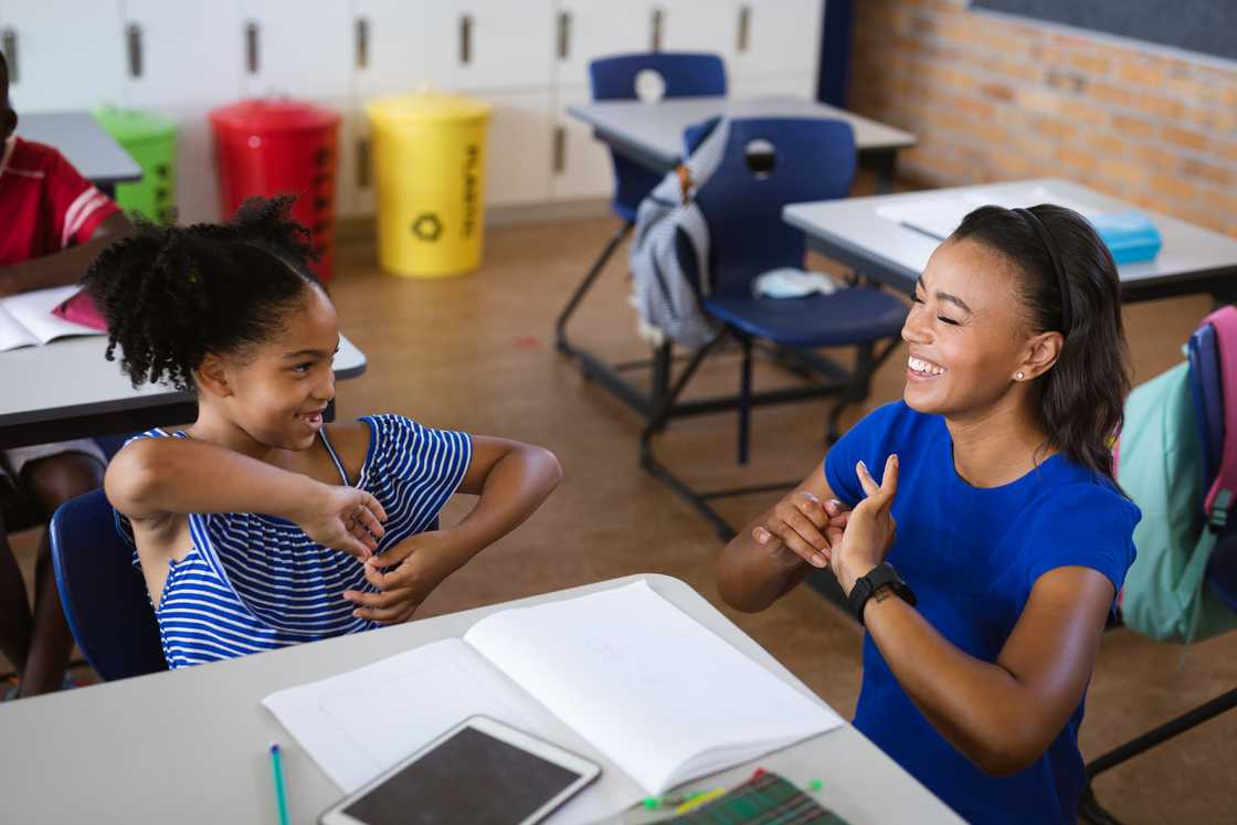 A young girl and teacher signing in class A young girl and teacher signing in class