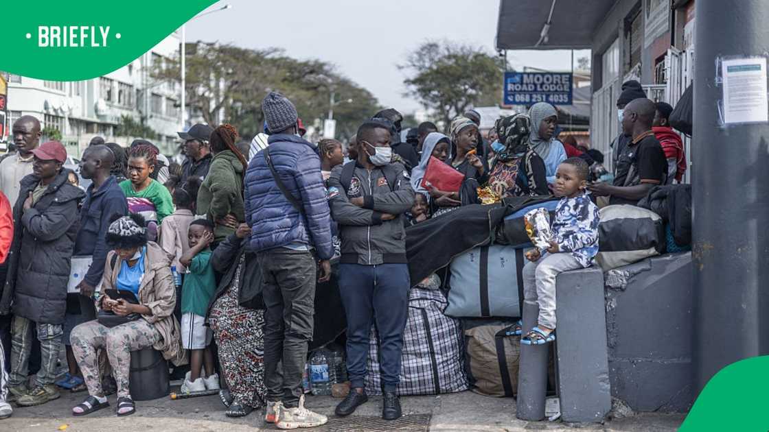 Foreign nationals stand by as they watch protestors from the anti-illegal immigration group, March and March Movement hold placards and chant slogans during a demonstration in Durban, on September 10, 2026