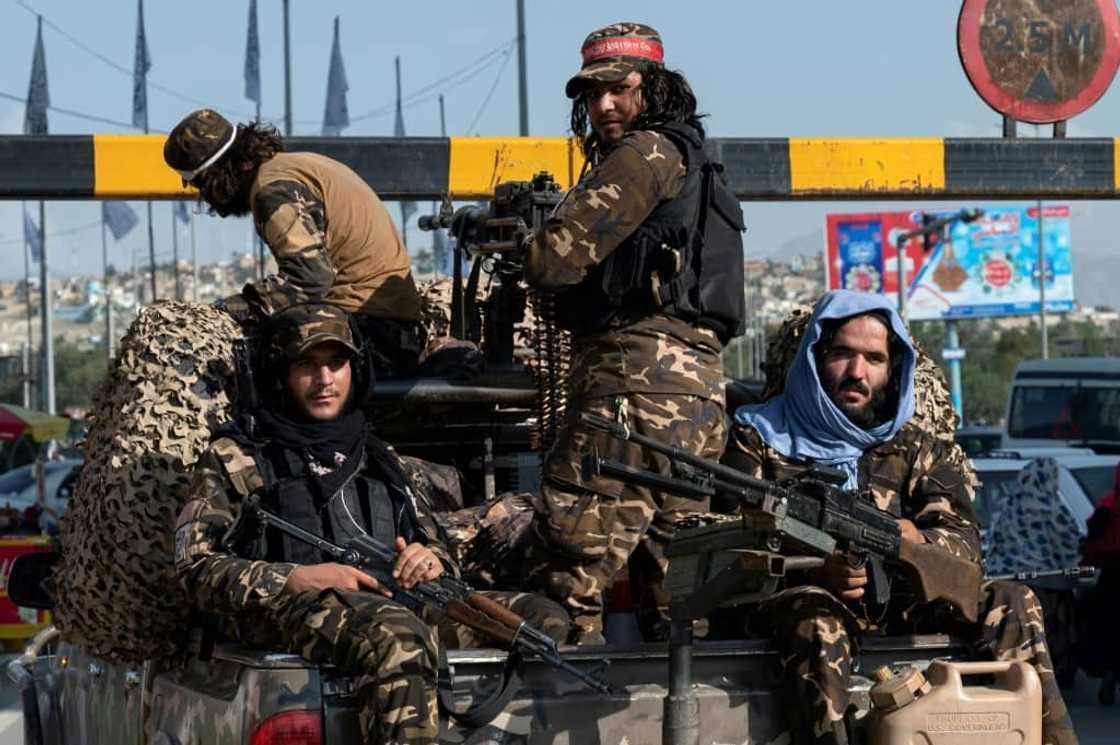 Taliban fighters travel along a road at the back of a pickup vehicle in Kabul Taliban fighters travel along a road at the back of a pickup vehicle in Kabul
