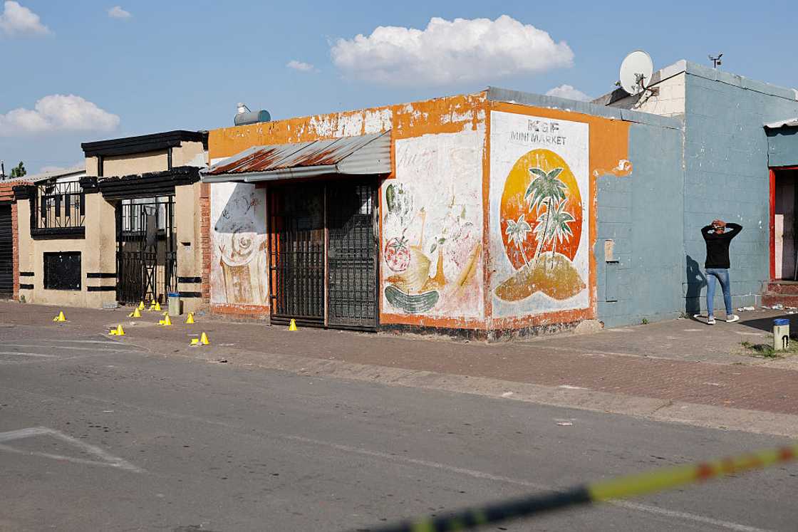 TOPSHOT - A resident walks near a crime scene in Westbury, near Johannesburg, on October 21, 2025. Six teenagers were shot at by unidentified suspects in Westbury on October 21, 2025 TOPSHOT - A resident walks near a crime scene in Westbury, near Johannesburg, on October 21, 2025. Six teenagers were shot at by unidentified suspects in Westbury on October 21, 2025