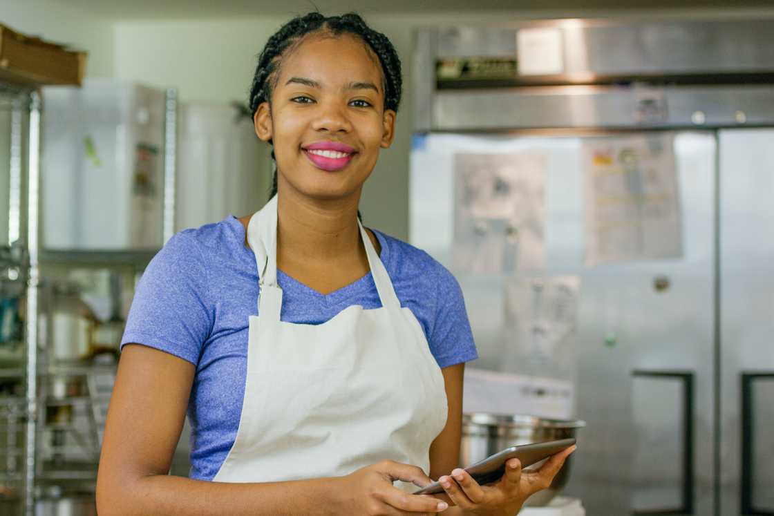 A young African American baker checks her sales