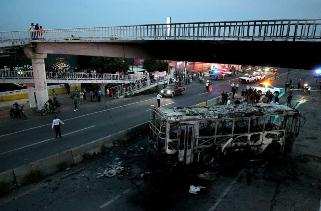 Police inspect an area where suspected gang members set a bus on fire in Mexico's western state of Jalisco