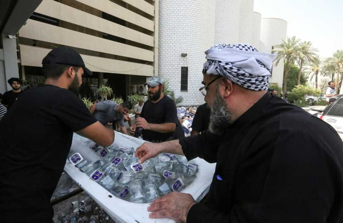 Supporters of Iraqi cleric Moqtada Sadr distribute water to fellow demonstrators, outside Iraq's parliament building on the second day of their occupation