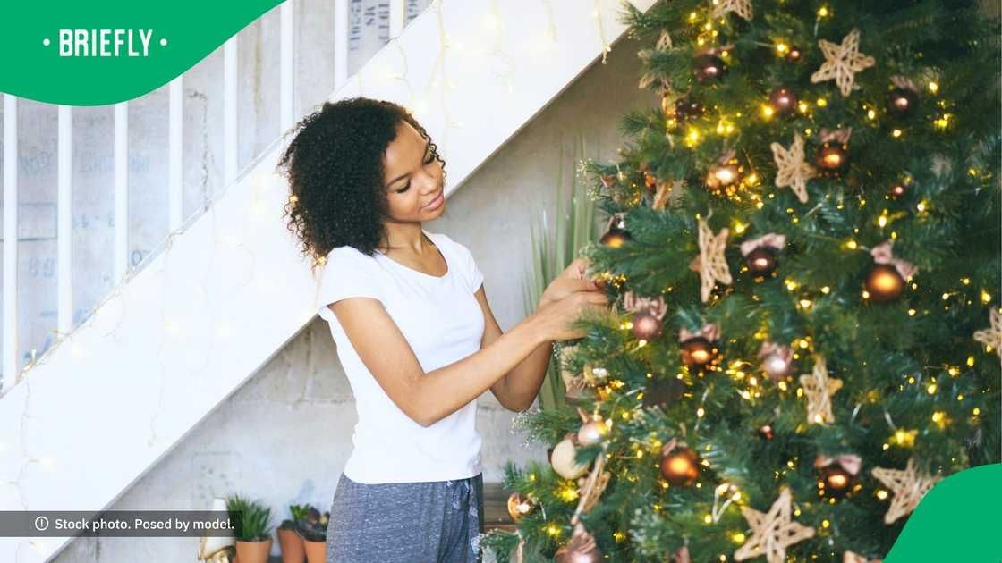 Mom and daughter build a Christmas tree from sticks and garland — a budget friendly memory in the making. Image: Unsplash