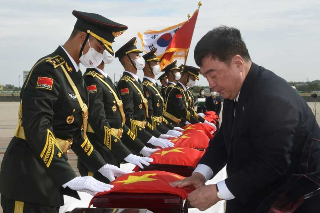 Chinese Ambassador to South Korea Xing Haiming (R) places his country's flag over caskets containing the remains of Chinese soldiers killed in the Korean War, during the handing over ceremony at South Korea's Incheon International Airport Chinese Ambassador to South Korea Xing Haiming (R) places his country's flag over caskets containing the remains of Chinese soldiers killed in the Korean War, during the handing over ceremony at South Korea's Incheon International Airport