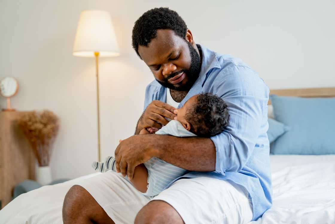 An African American father holds a newborn baby An African American father holds a newborn baby