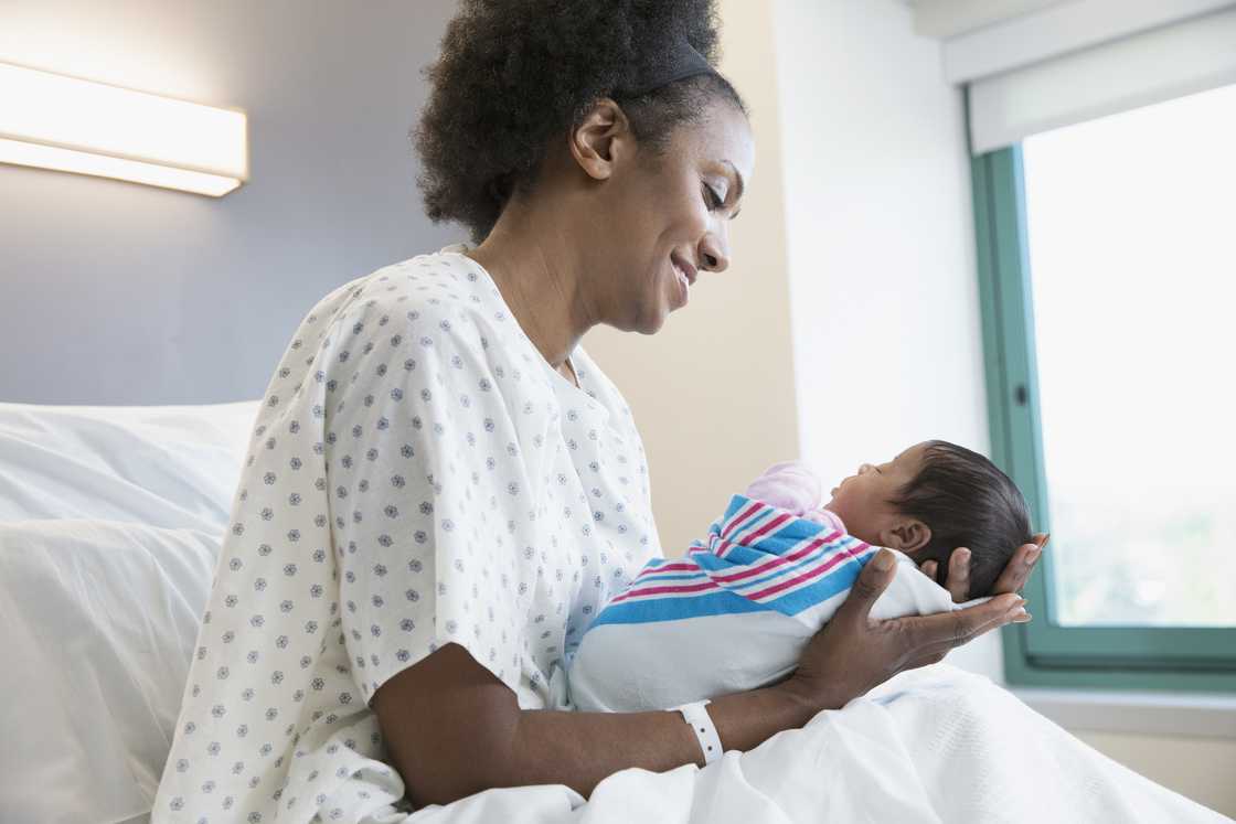 A young mother holding her newborn lovingly.