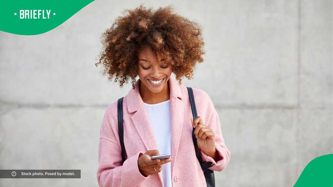 A woman smiling at her phone. A woman smiling at her phone.
