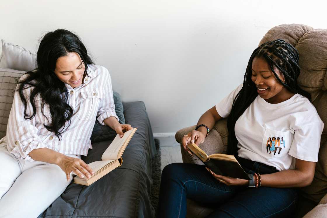 Two multi-ethnic women are reading books on couches