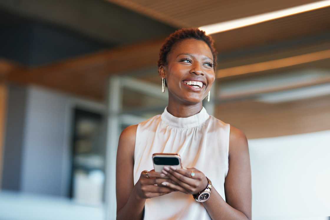 A woman smiling at her phone.