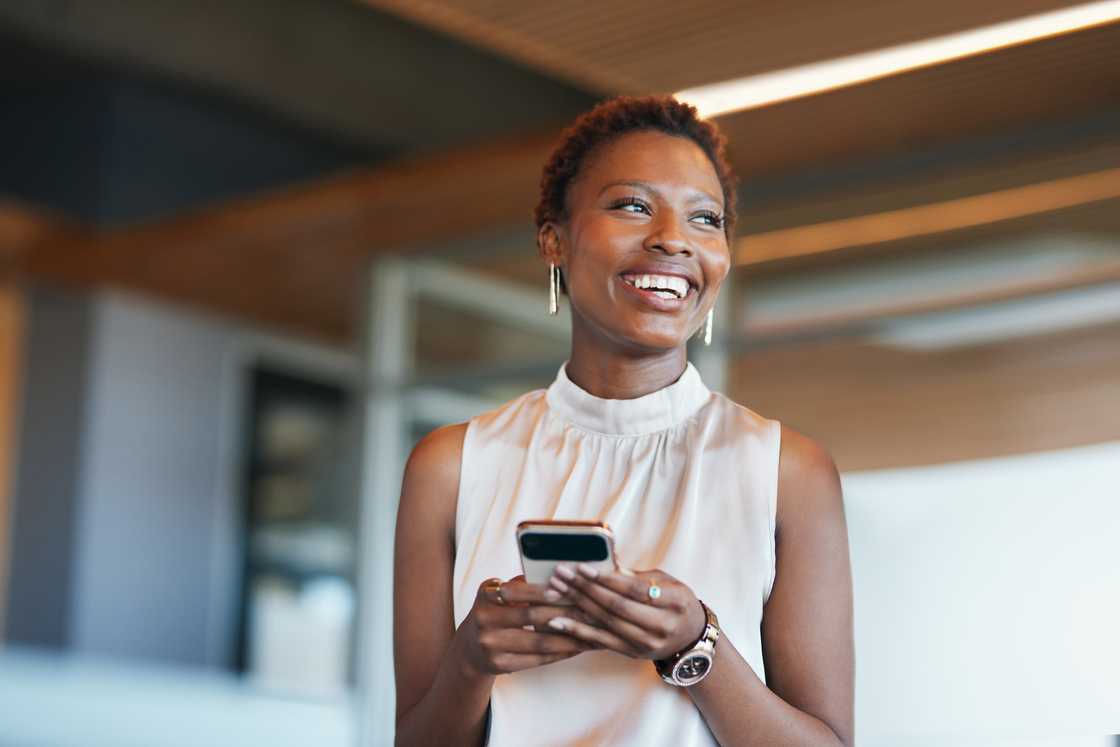 A woman smiling at her phone. A woman smiling at her phone.