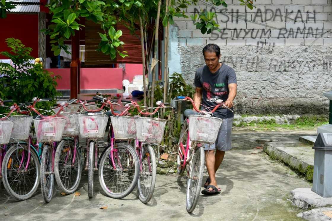 Edi Mulyono stands next to a sign that reads: "Is there still a friendly smile for the people?", written as a protest against environmental issues faced by Pari islanders Edi Mulyono stands next to a sign that reads: "Is there still a friendly smile for the people?", written as a protest against environmental issues faced by Pari islanders