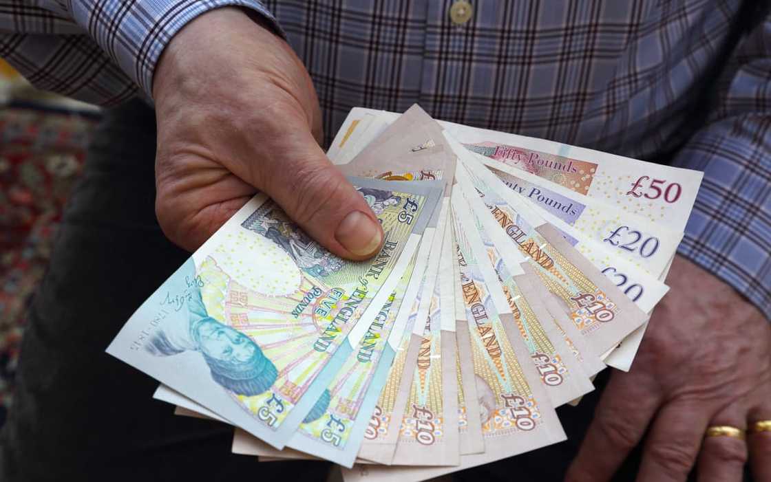 A senior male holding British banknotes in his right hand A senior male holding British banknotes in his right hand