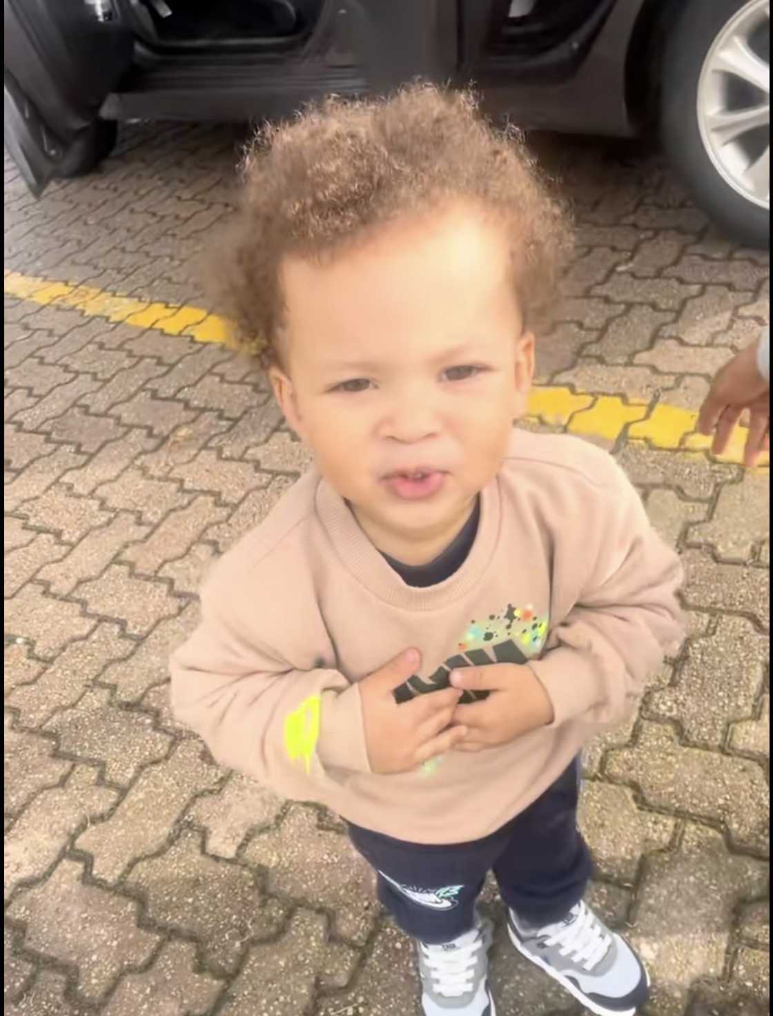 A kid chilled next to his dad's car