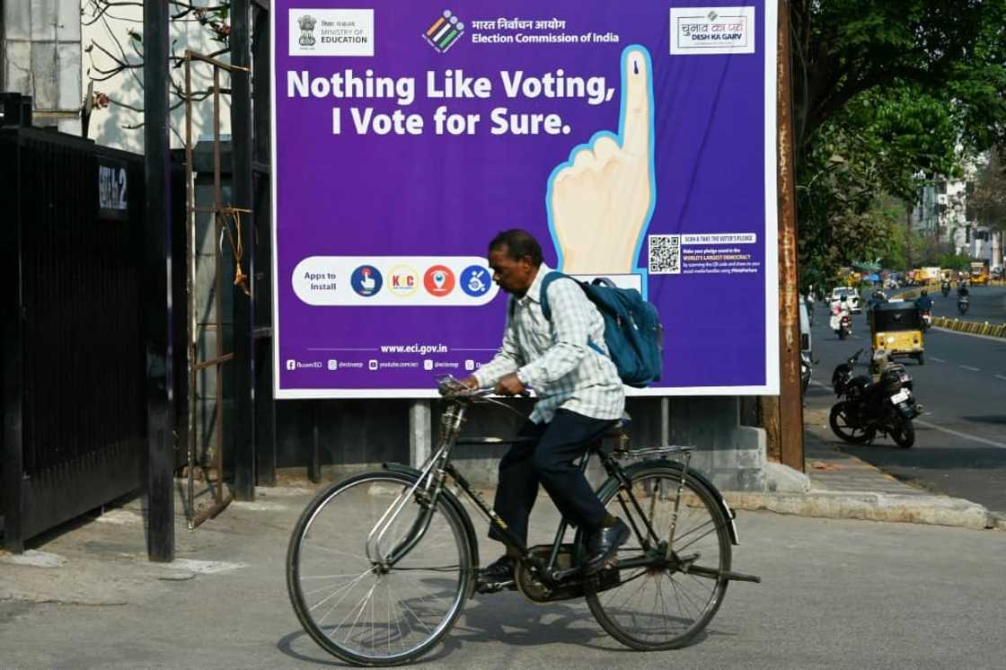 A man rides past an election awareness poster displayed on a street ahead of India’s upcoming general elections, in Hyderabad