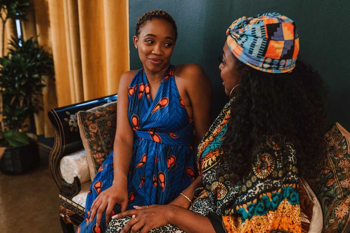Adult daughter sitting across from her mother in a quiet living room. Adult daughter sitting across from her mother in a quiet living room.