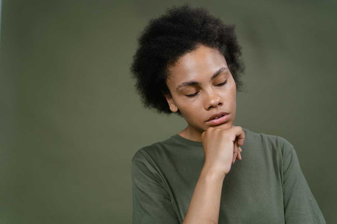 A young woman rests her chin on her hand while thinking deeply.