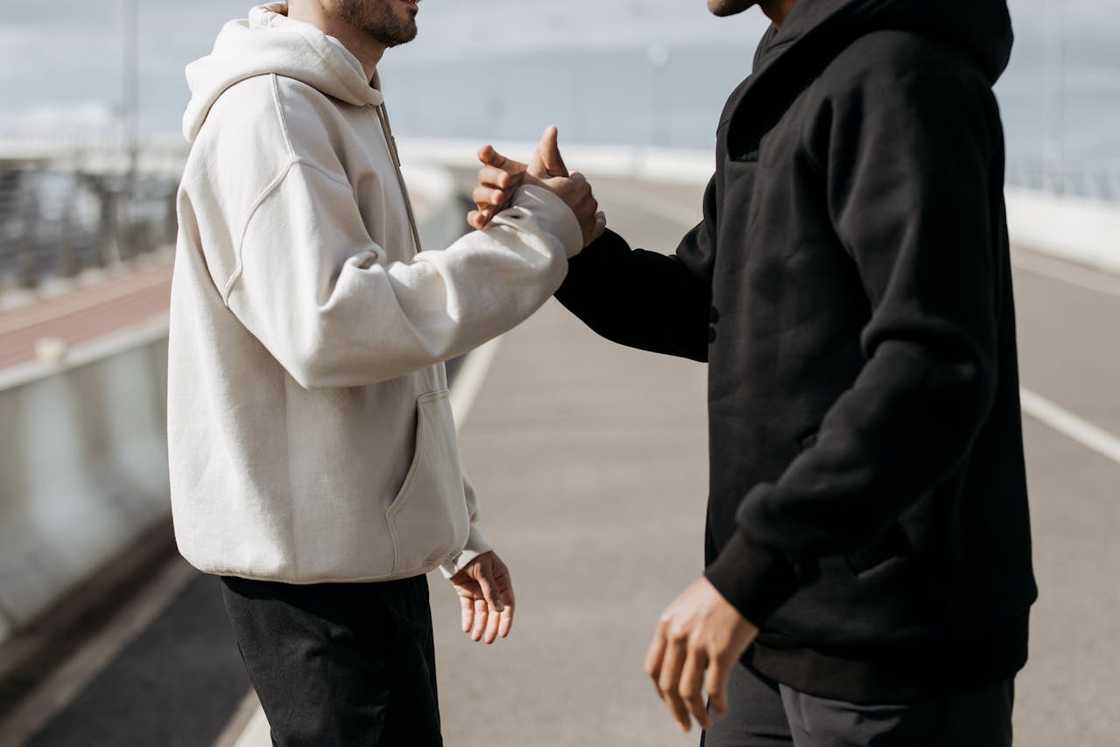 Two men greeting each other with a handshake outdoors.