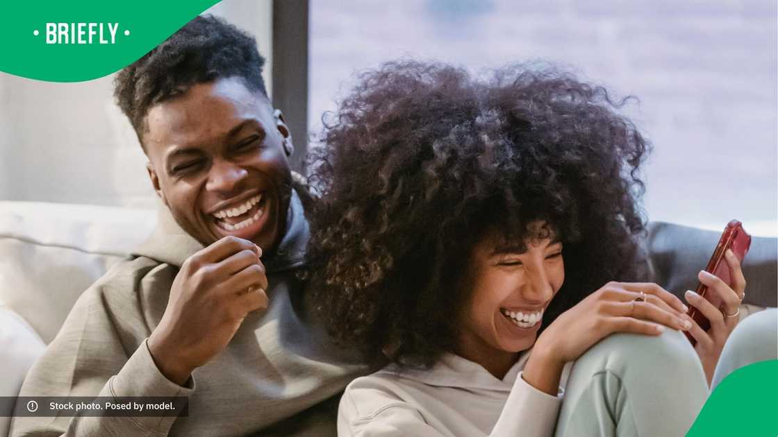 A couple laughing at a phone.
