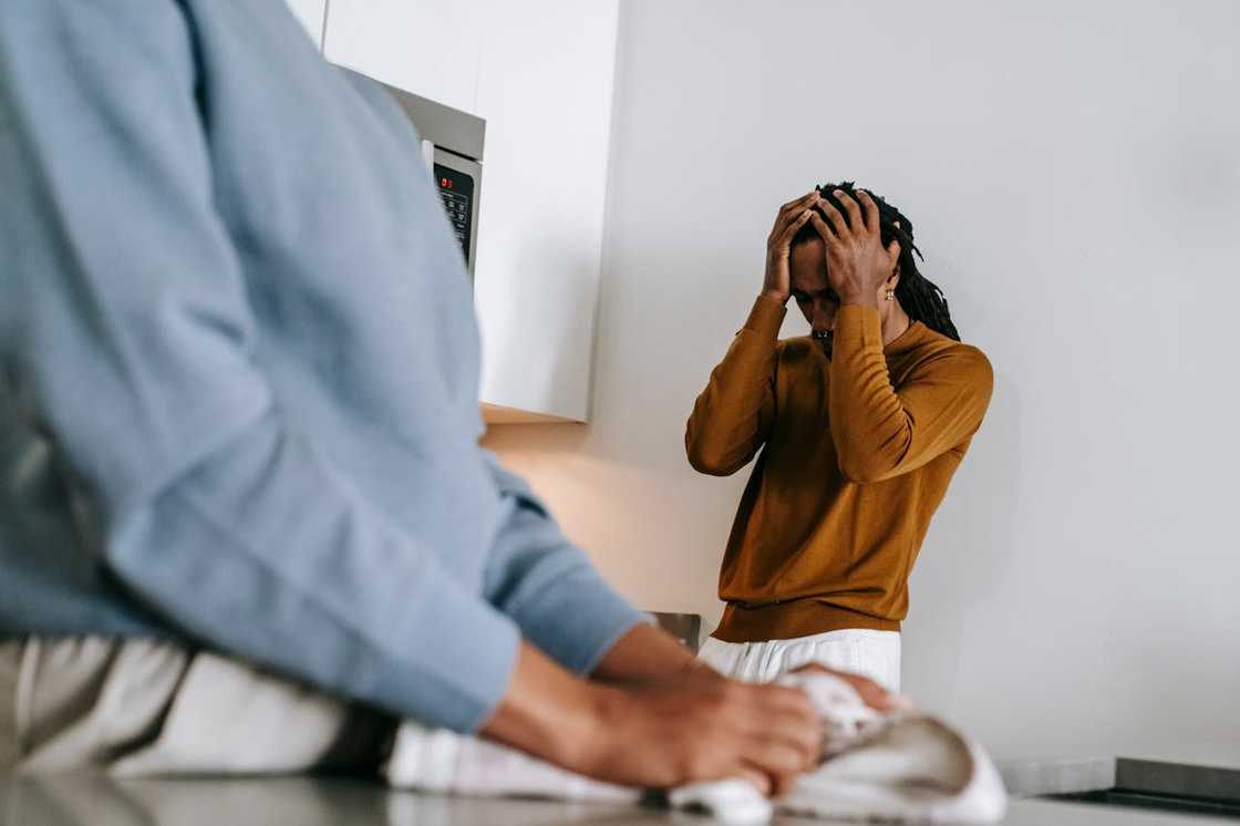 A man reacts in distress while his mother looks on. A man reacts in distress while his mother looks on.