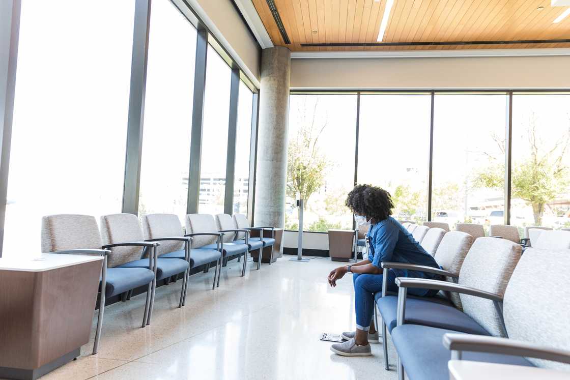 A woman sits apart at the hospital waiting area.