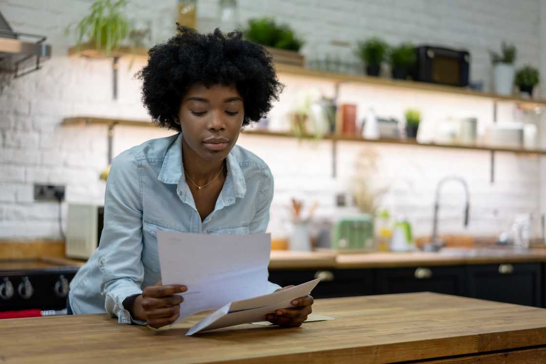 A woman reads a letter at home.
