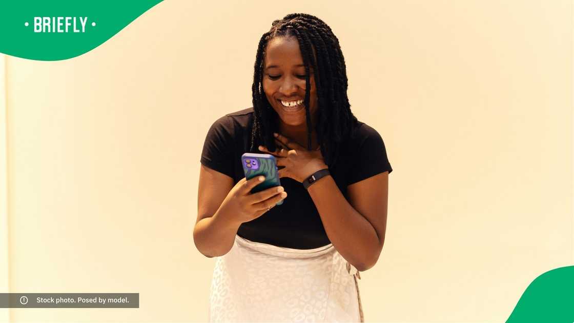 A woman smiling at her phone.